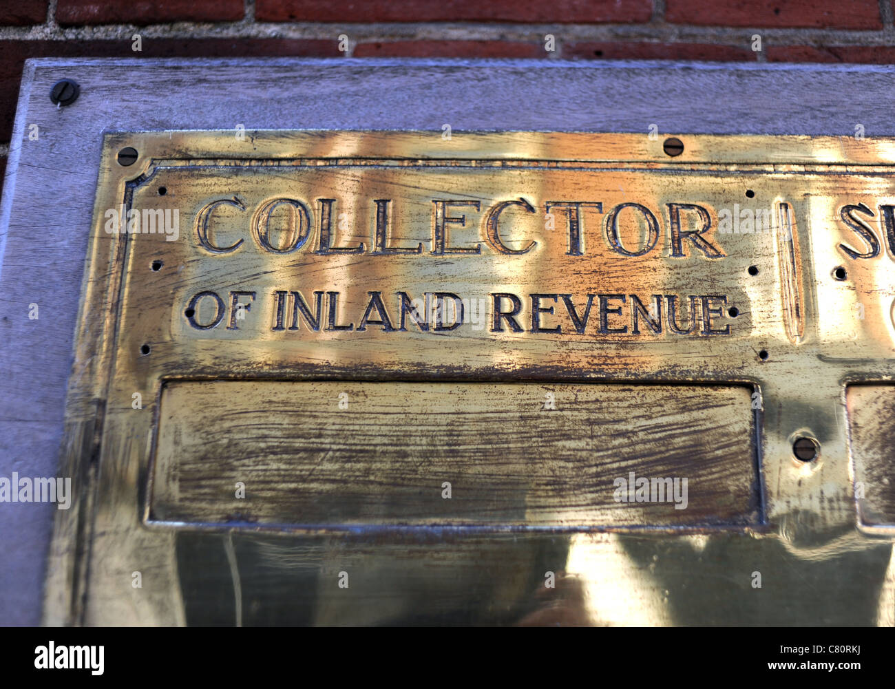 Collettore di Inland Revenue le tasse nel Regno Unito su un segno di ottone piastra contro una parete Foto Stock