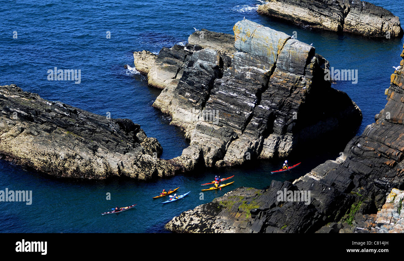 Canoisti passano tra le rocce a sud di stack, Anglesey, Galles del Nord Foto Stock