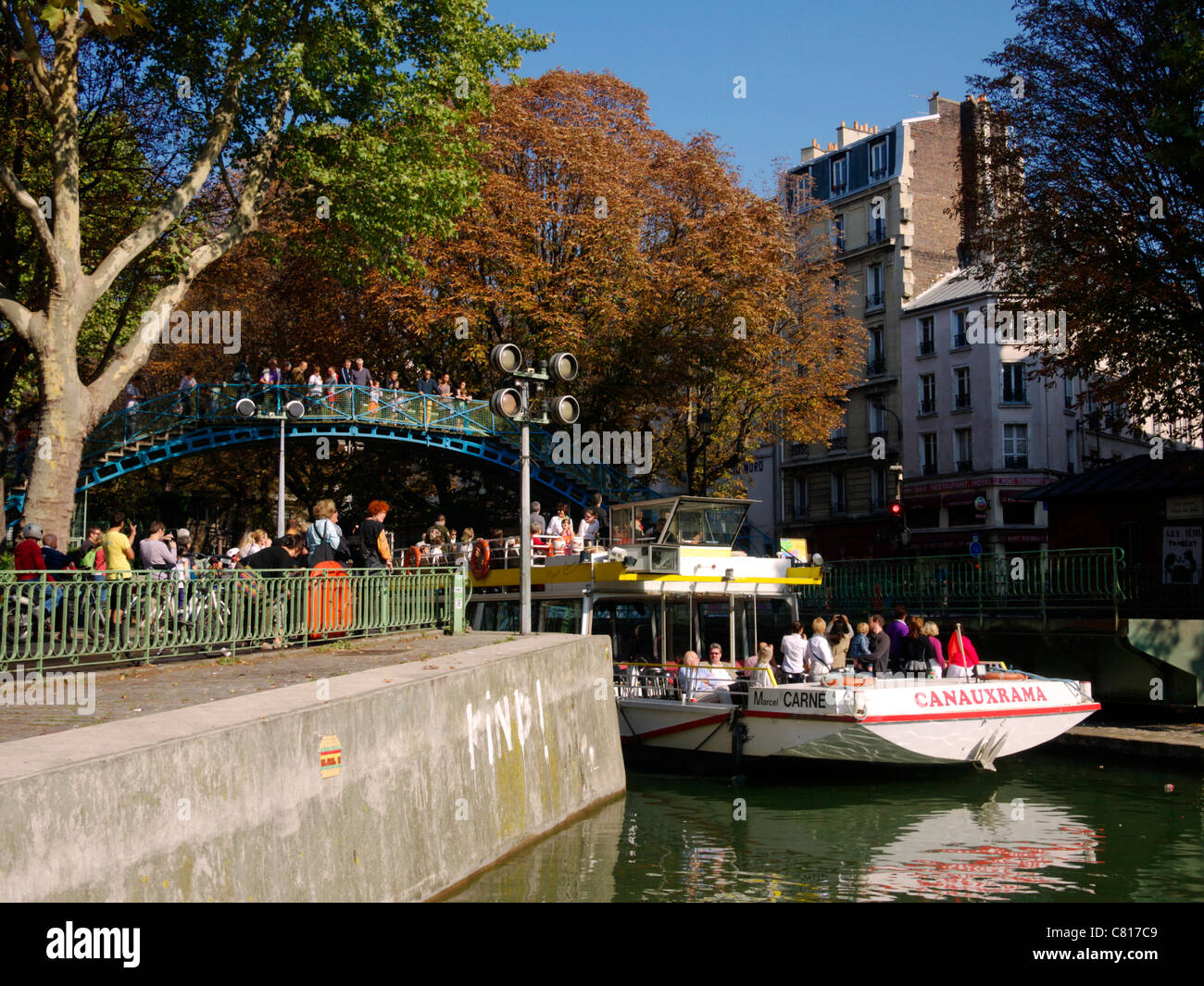 La gente guarda come una barca turistica passa lungo il Canal Saint Martin, Paris Foto Stock