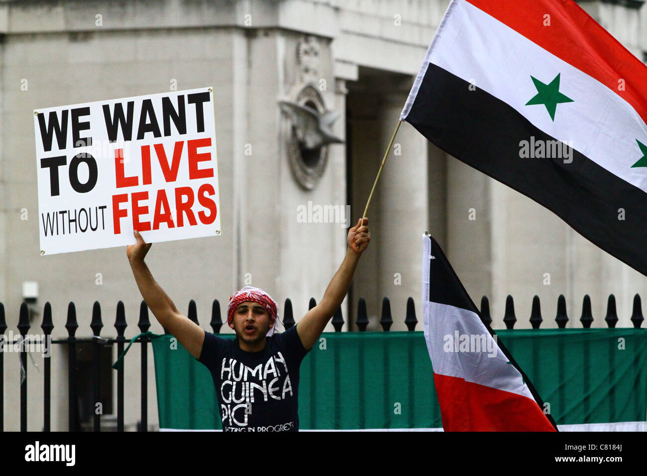 Un manifestante detiene una targhetta e le onde la bandiera siriana di fronte a Downing Street, Londra, 201. Foto Stock