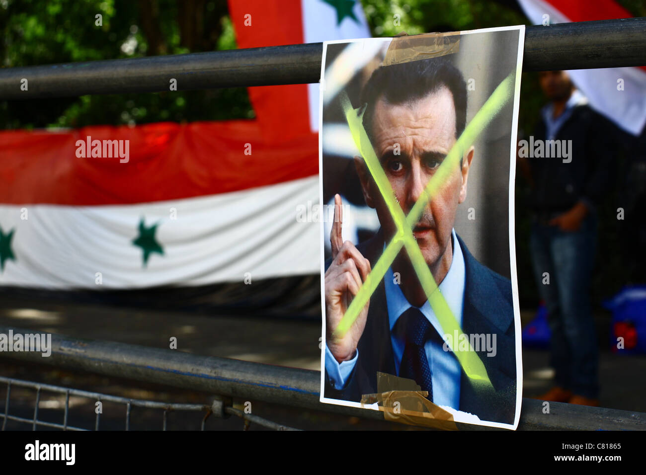 Un cassonetto con le foto del Presidente siriano Bashar al-Assad è visualizzato di fronte l'Ambasciata siriana a Londra. Foto Stock