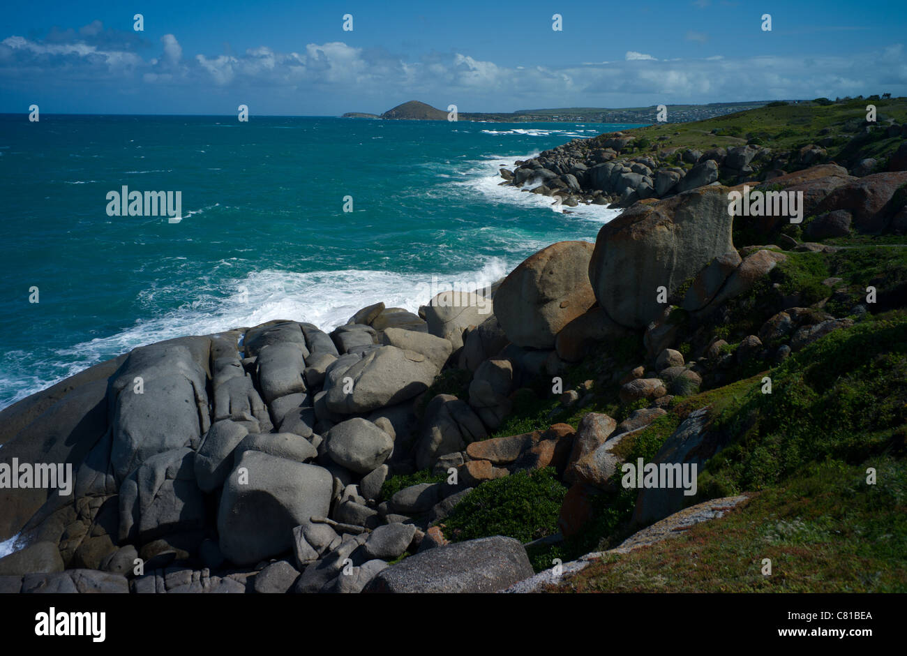 Vista del mare da Isola di granito con onde che si infrangono sulle rocce e il bluff visibile in distanza. Foto Stock