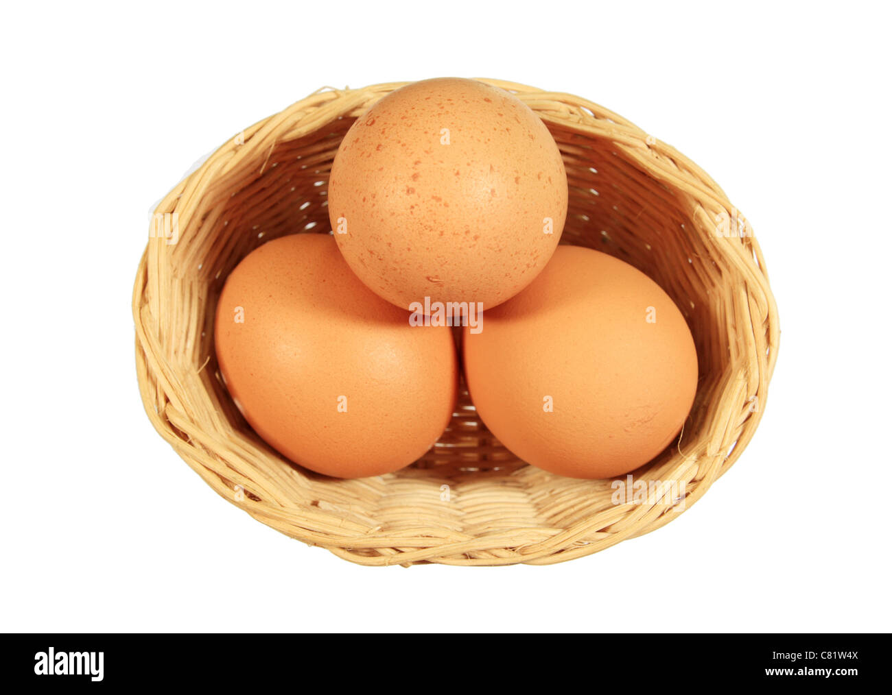 Tre uova marrone in un piccolo cesto in vimini isolato su bianco Foto Stock