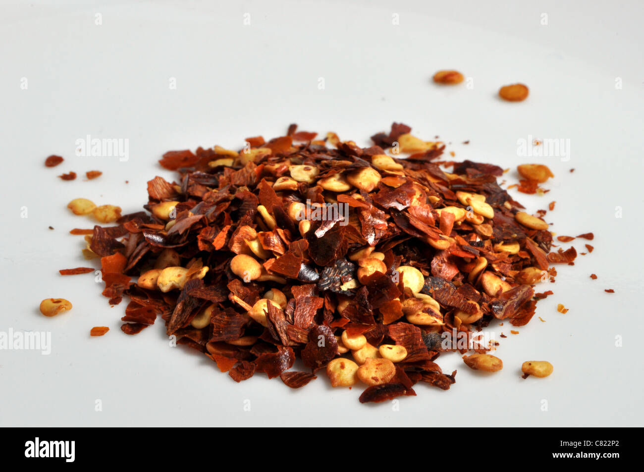 Peperoncino rosso tritato giace su un semplice sfondo bianco Foto Stock