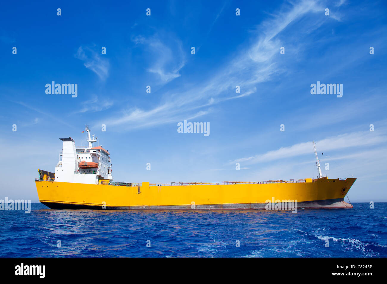 Ancoraggio giallo carico barca in mare blu sotto il cielo di estate Foto Stock