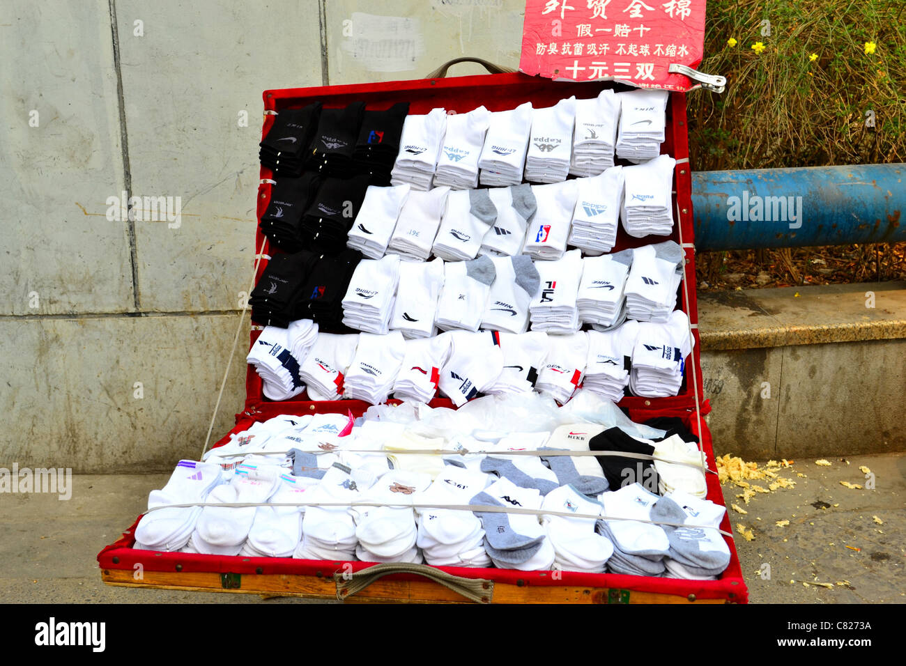 Neat cercando calzini dalle principali marche di essere venduti al di fuori di un box in una sudicia street. Foto Stock