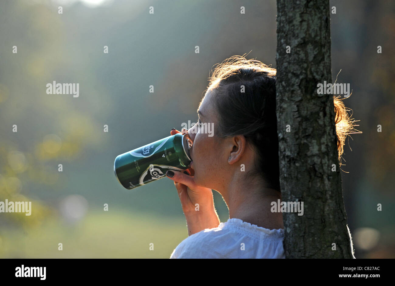 Giovane donna fuori in un parco pubblico di bere dalla possibile di birra lager Queens Pk Brighton - poste da modello a modello Foto Stock