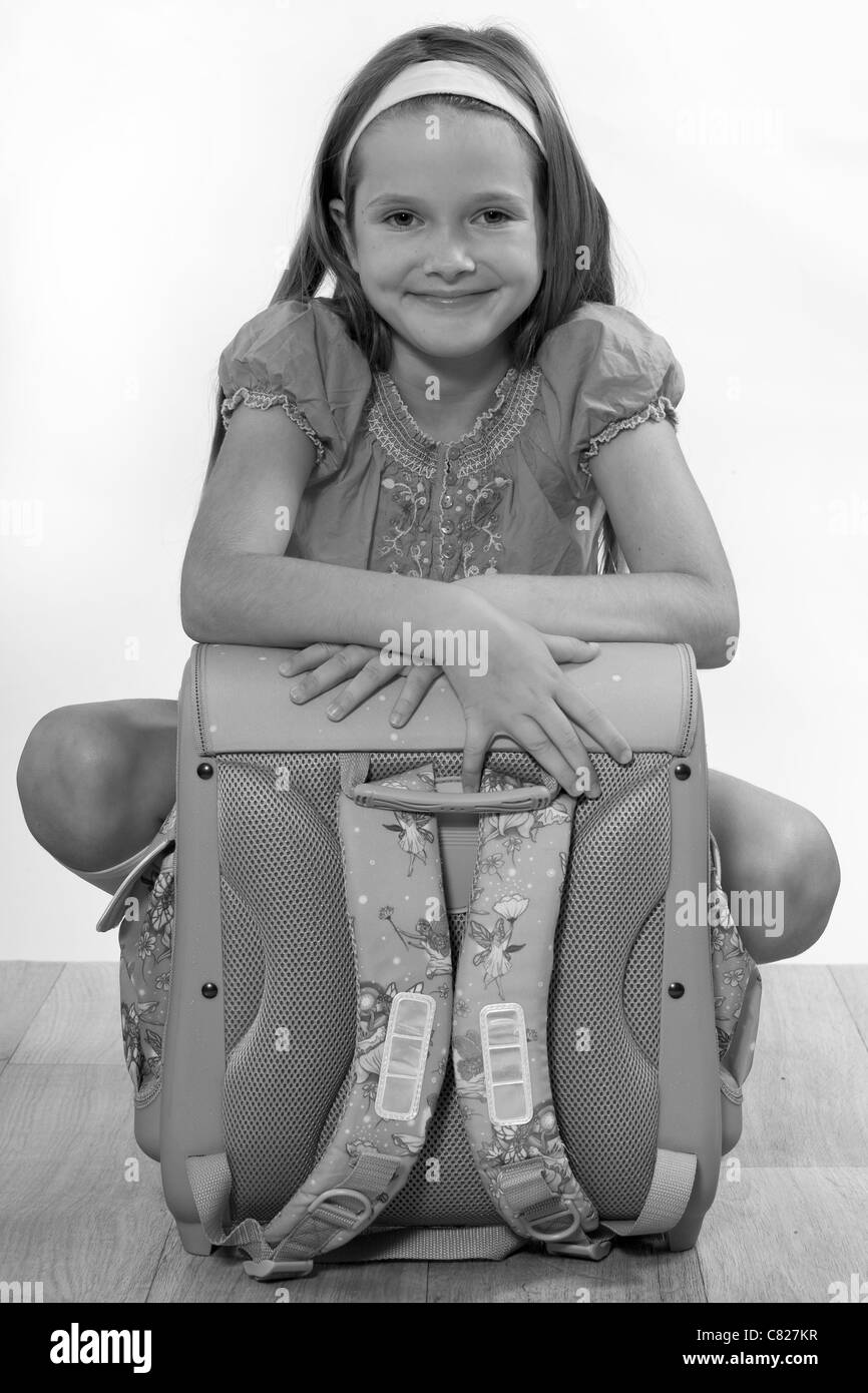Otto anni di ragazza seduta con una tasca sul pavimento Foto Stock