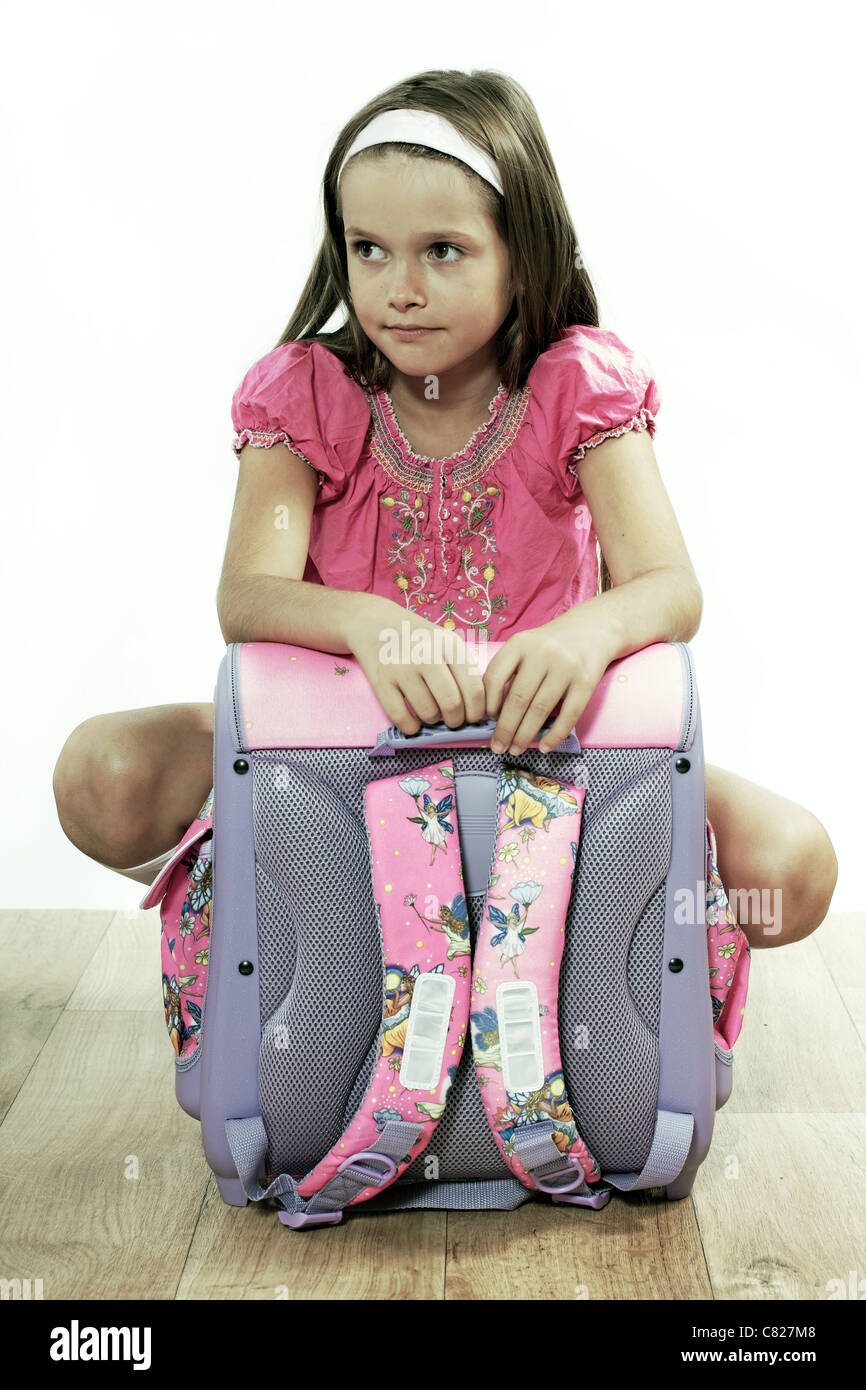 Otto anni di ragazza seduta con una tasca sul pavimento Foto Stock