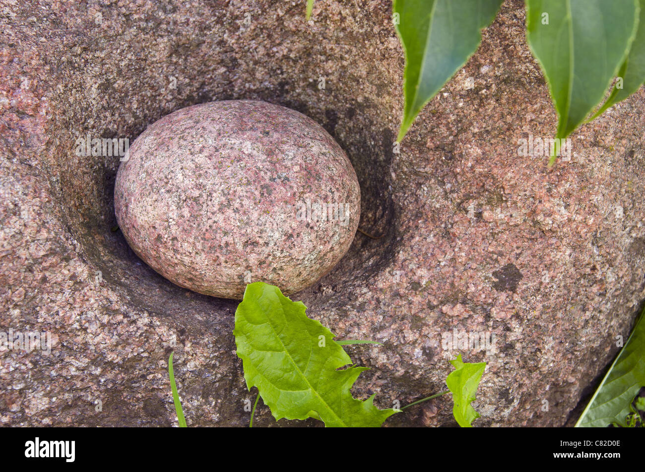 Piccola pietra tonda in quella grande. Il vecchio strumento tradizionale per la macinazione di grano. Foto Stock