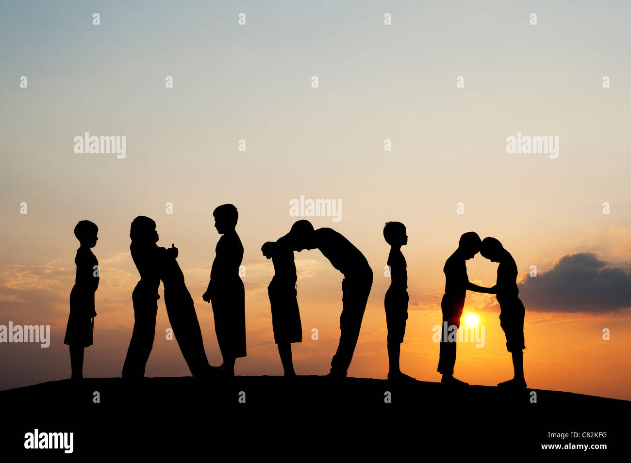 Silhouette di 9 ragazzi l'ortografia della parola INDIA al tramonto. India Foto Stock