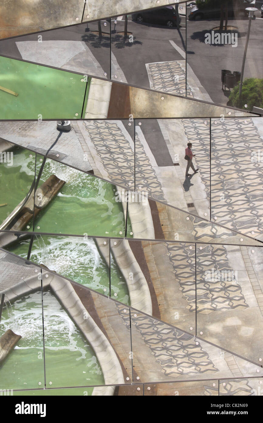 Finestra di interessanti riflessioni con acqua verde e un uomo su un marciapiede piastrellato Foto Stock