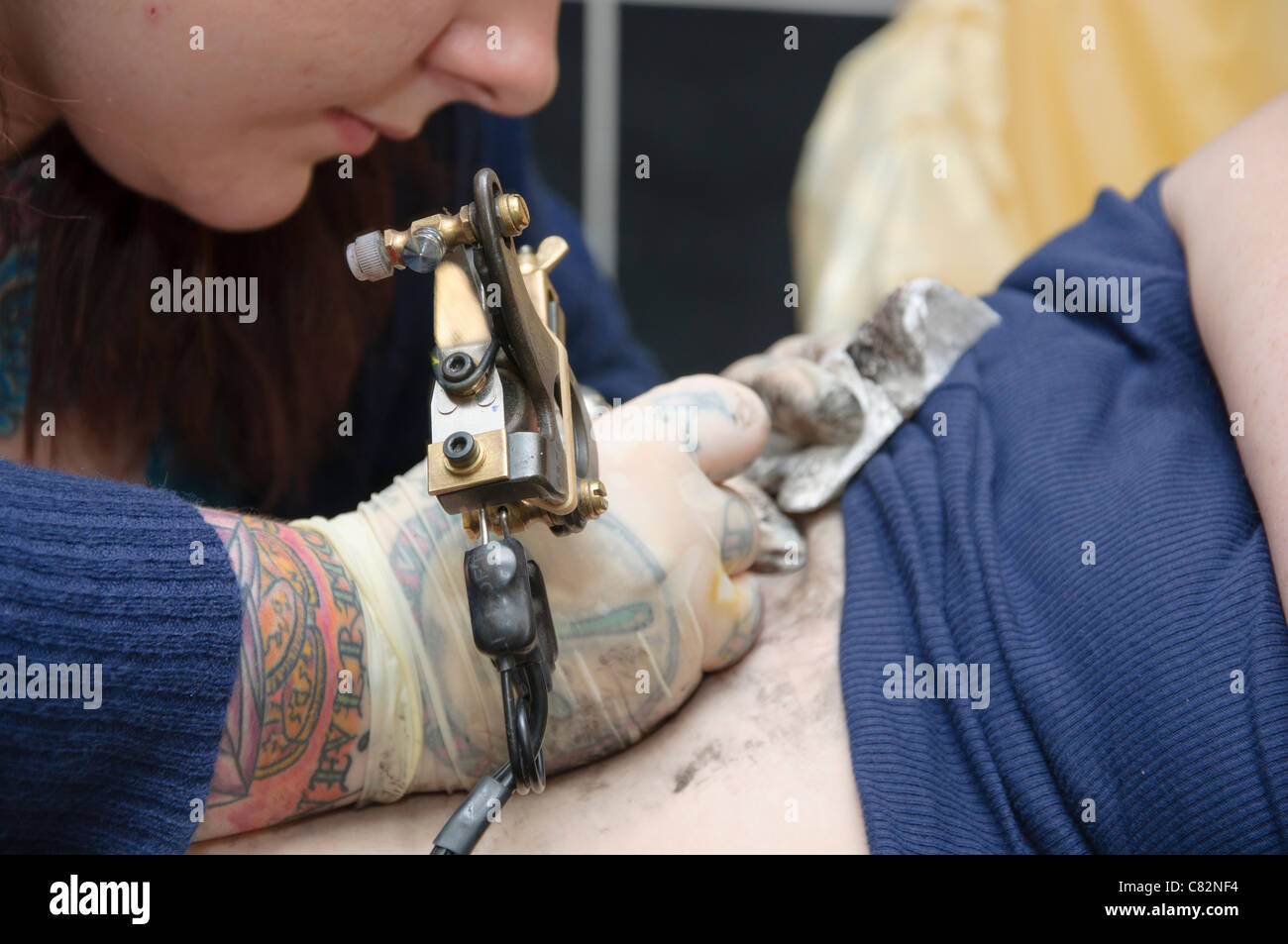 Femmina di ottenere un betty boop tatuaggio sul suo lato inferiore destro mostra tattoo artist in azione Foto Stock