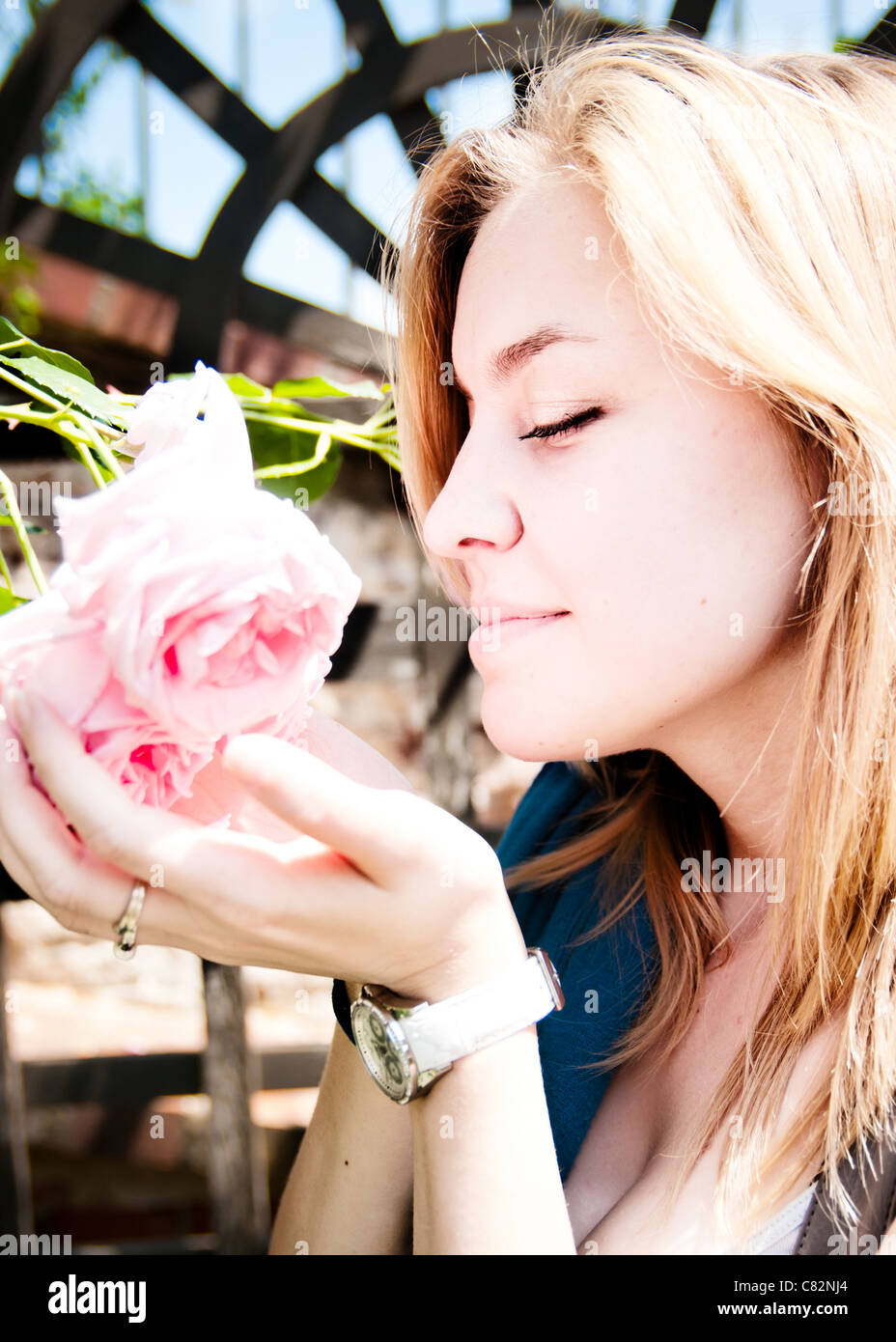 Piuttosto giovane donna odorare una rosa Foto Stock