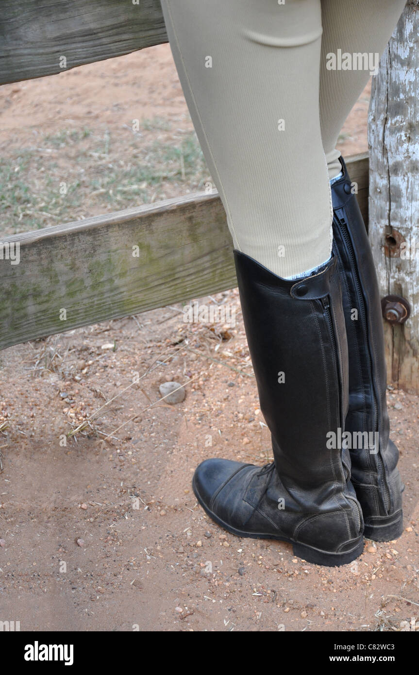 Una persona che indossa l'inglese stivali da cavallo in piedi contro un  recinto in legno su un terreno sporco Foto stock - Alamy