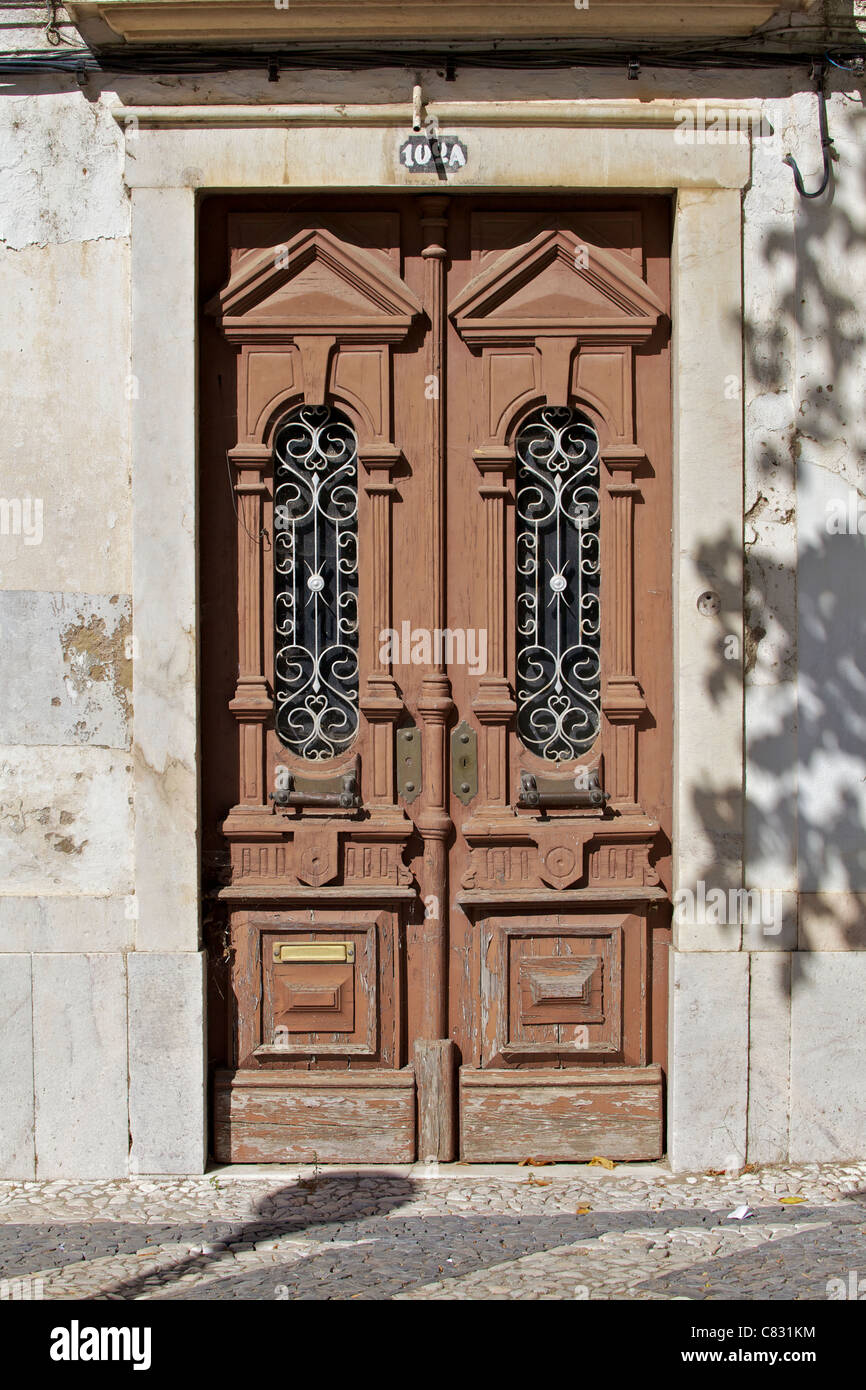 Weathered marrone porta in legno con maniglie in ottone nella città medievale di Estremoz Foto Stock