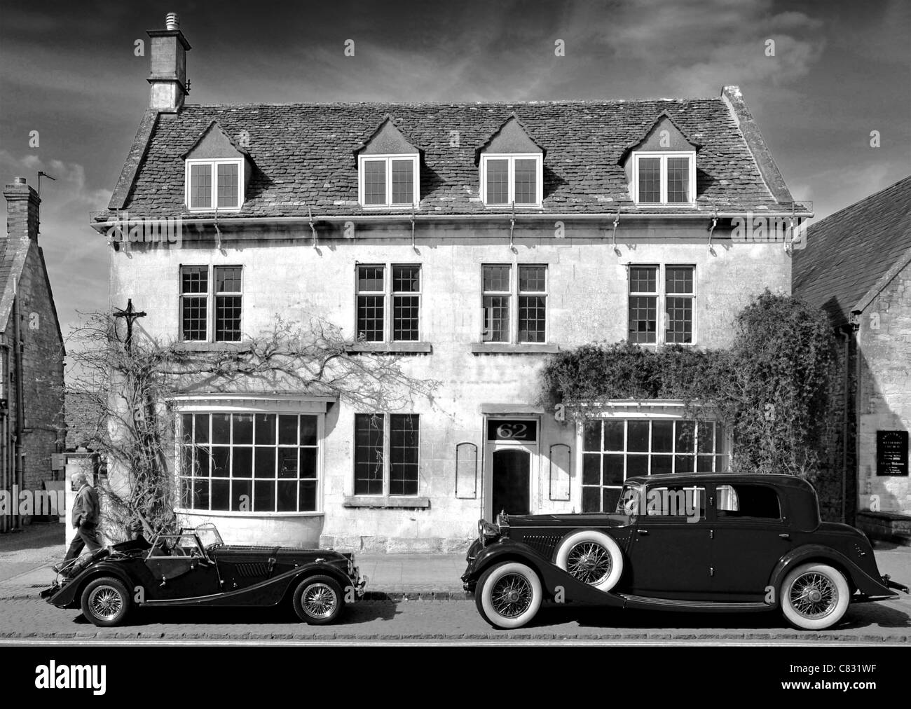 Due classiche auto parcheggiate al di fuori di un edificio storico, Broadway, Cotswolds. Disponibile a colori e in bianco e nero. Foto Stock