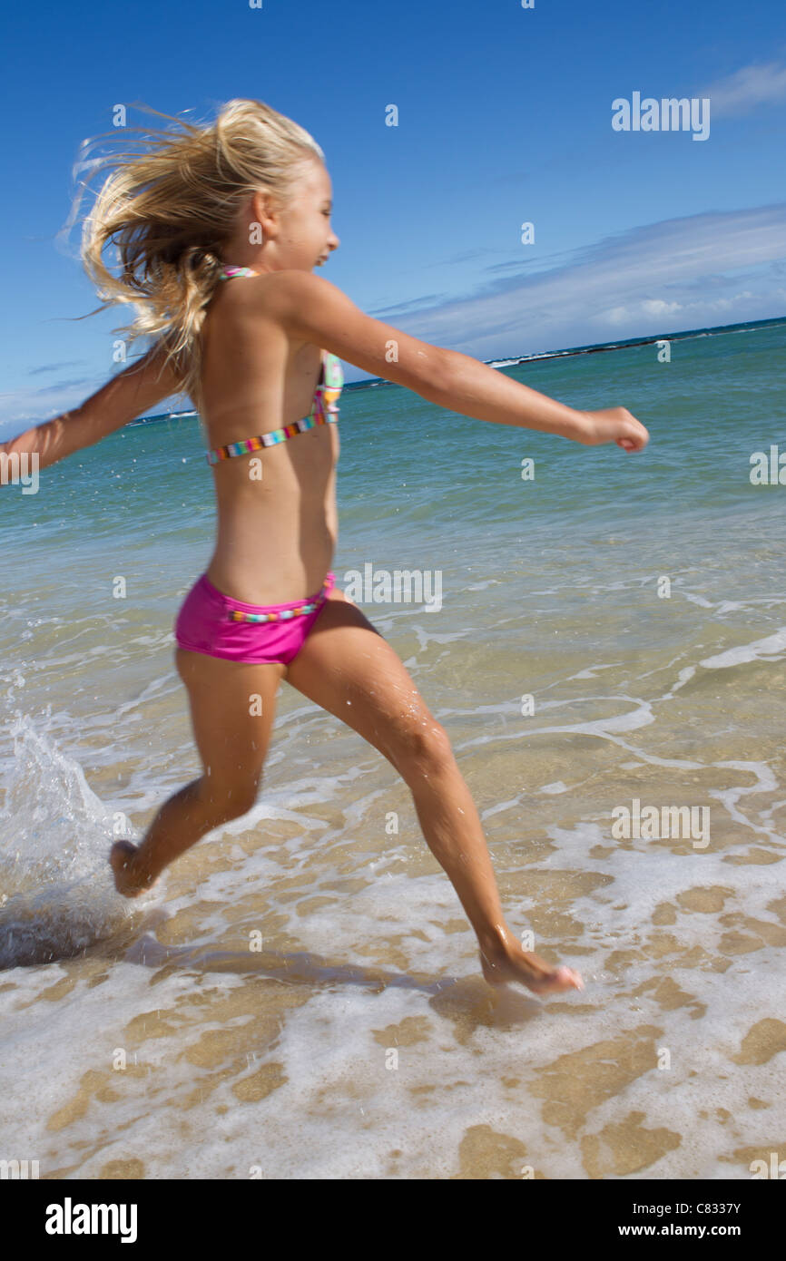 Ragazza che corre e gioca su una spiaggia a Maui Foto Stock
