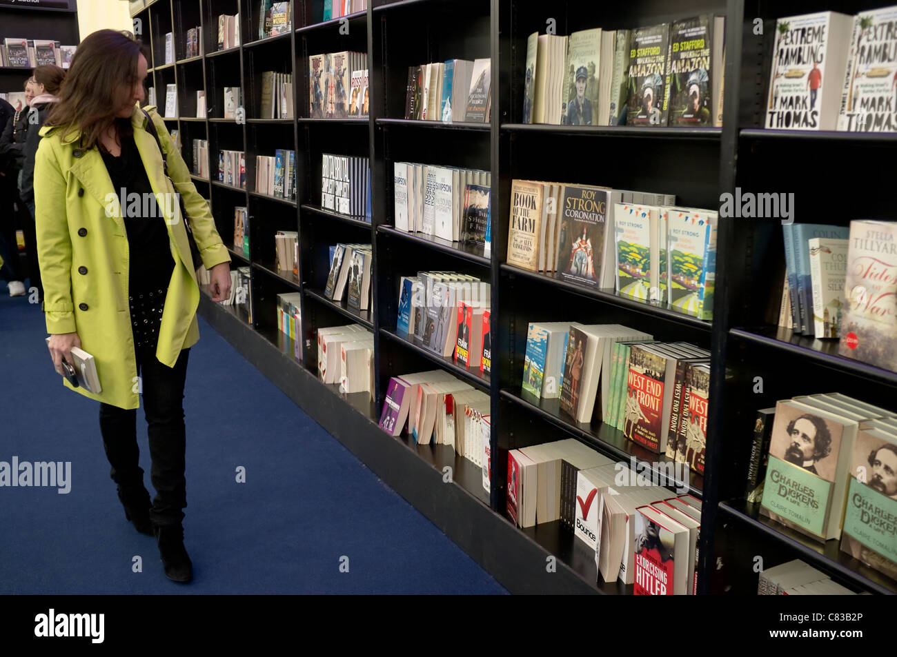 Una donna in Waterstone's book shop / tenda, guardando e preparazione di acquistare libri a Cheltenham Festival della letteratura. Foto Stock