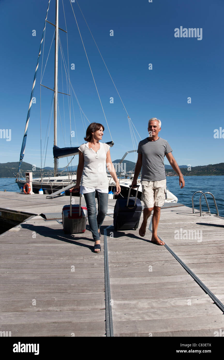 Anziana coppia di rotolamento sui bagagli pier Foto Stock