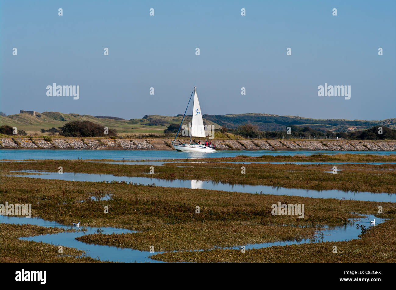 Vista laterale di uno yacht a vela vela sul fiume Rother ad alta marea dal porto di segale Riserva Naturale East Sussex Regno Unito Foto Stock