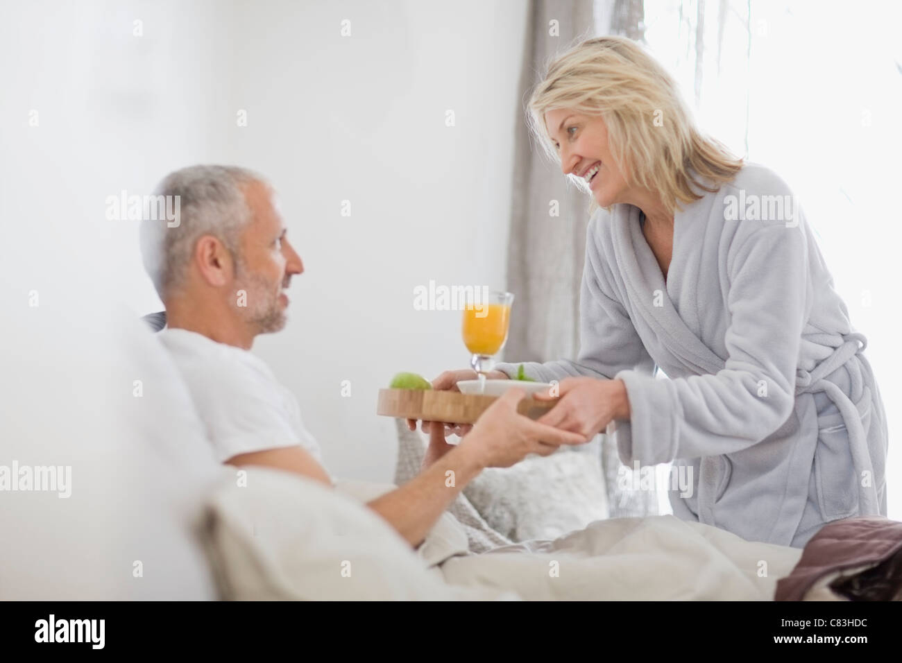 Donna portare marito colazione a letto Foto Stock