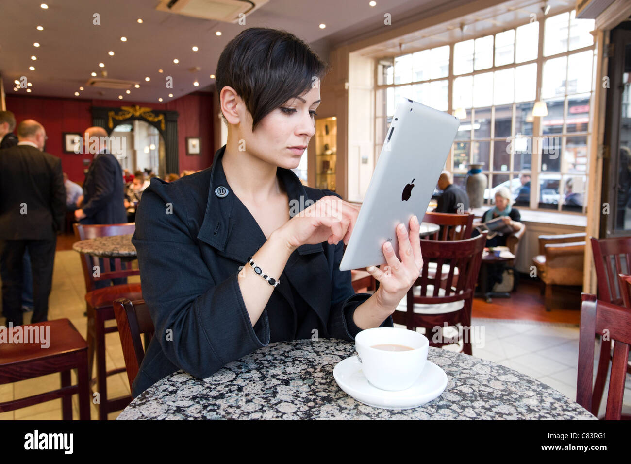Giovane donna navigando in Internet su un iPad di Apple Computer tablet utilizzando coffee shop gratuito wi fi, London, Regno Unito Foto Stock