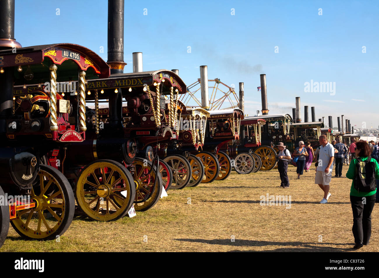 Fila di 18 motori a vapore ad una fiera a vapore con persone di ammirare sotto il cielo blu Foto Stock