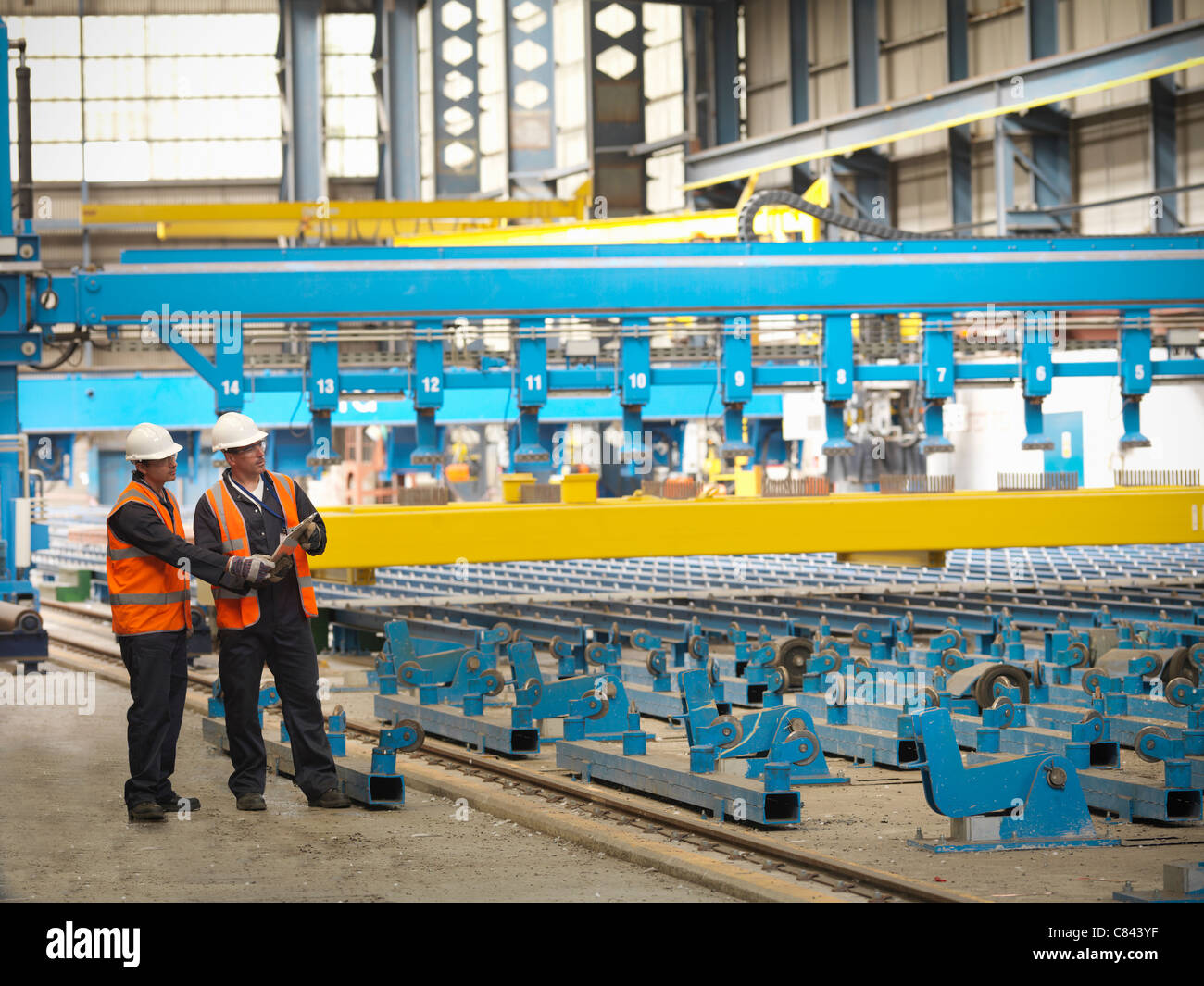 Lavoratori esaminando macchine di costruzione navale Foto Stock