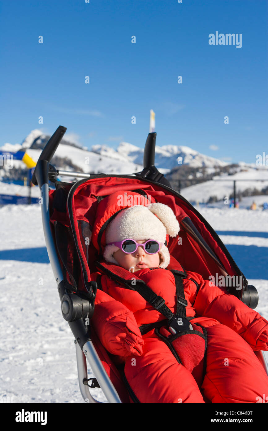 1 anno di età bambina a prendere il sole, Compaccio, Alpe di Siusi, Mont Seuc in ladino, Dolomiti dell Alto Adige, Italia, inverno Foto Stock