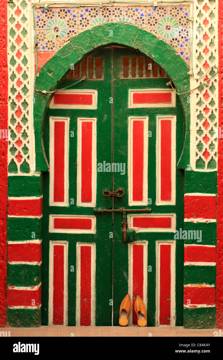 Marocchino tradizionale pantofole/babouches contro di legno e mattonelle porta marocchina nella medina di Essaouira, Marocco, Africa del nord Foto Stock