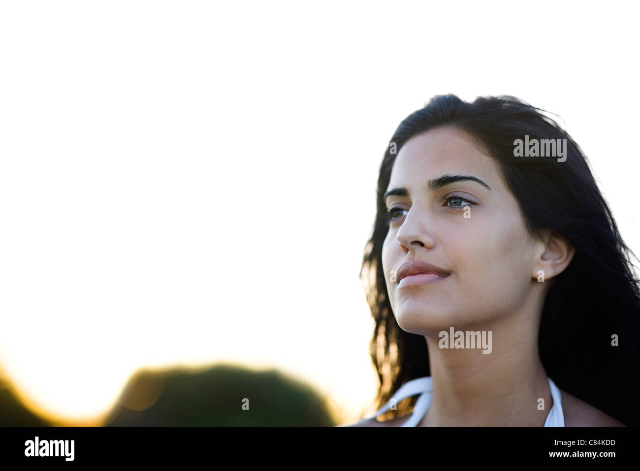 Giovane donna che guarda lontano con soddisfazione, ritratto Foto Stock