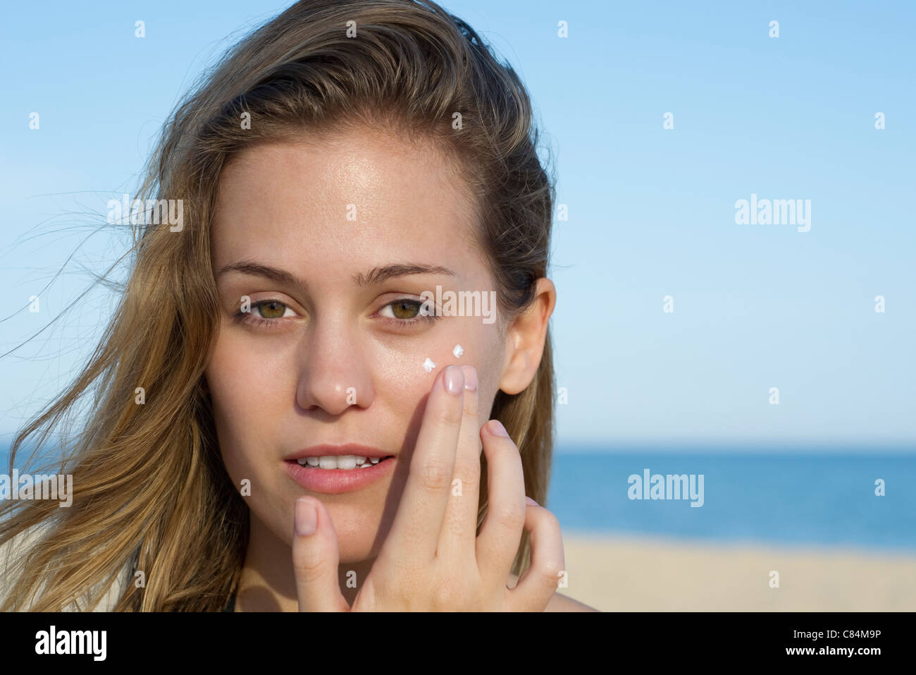 Donna l'applicazione di crema solare in spiaggia, ritratto Foto Stock