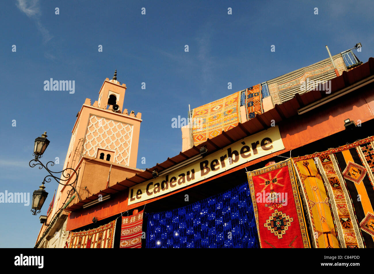 Le Cadeau Berbere negozio di tappeti e moschea, Piazza Djemaa el Fna a Marrakech, Marocco Foto Stock
