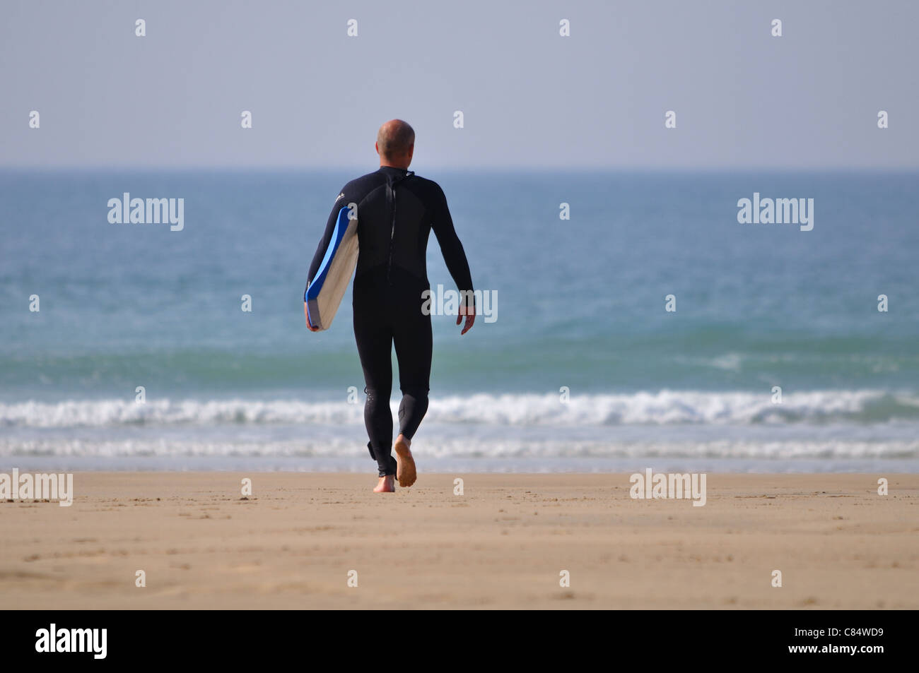 Un unico maschio con bodyboard sotto braccio rendendo la sua via di uscita al mare Foto Stock