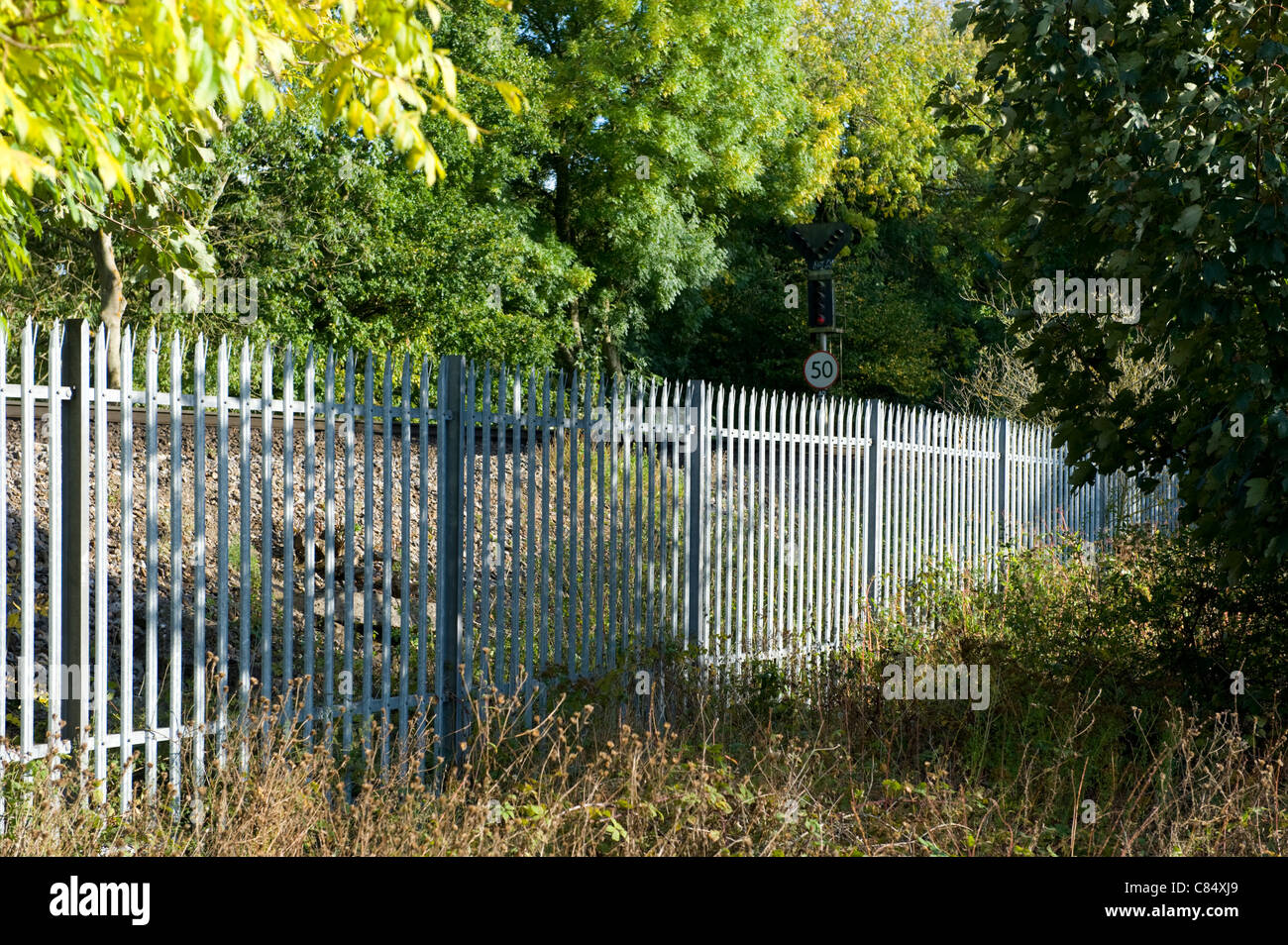Non verniciata recinzione ferroviaria a fianco di una linea ferroviaria principale Foto Stock