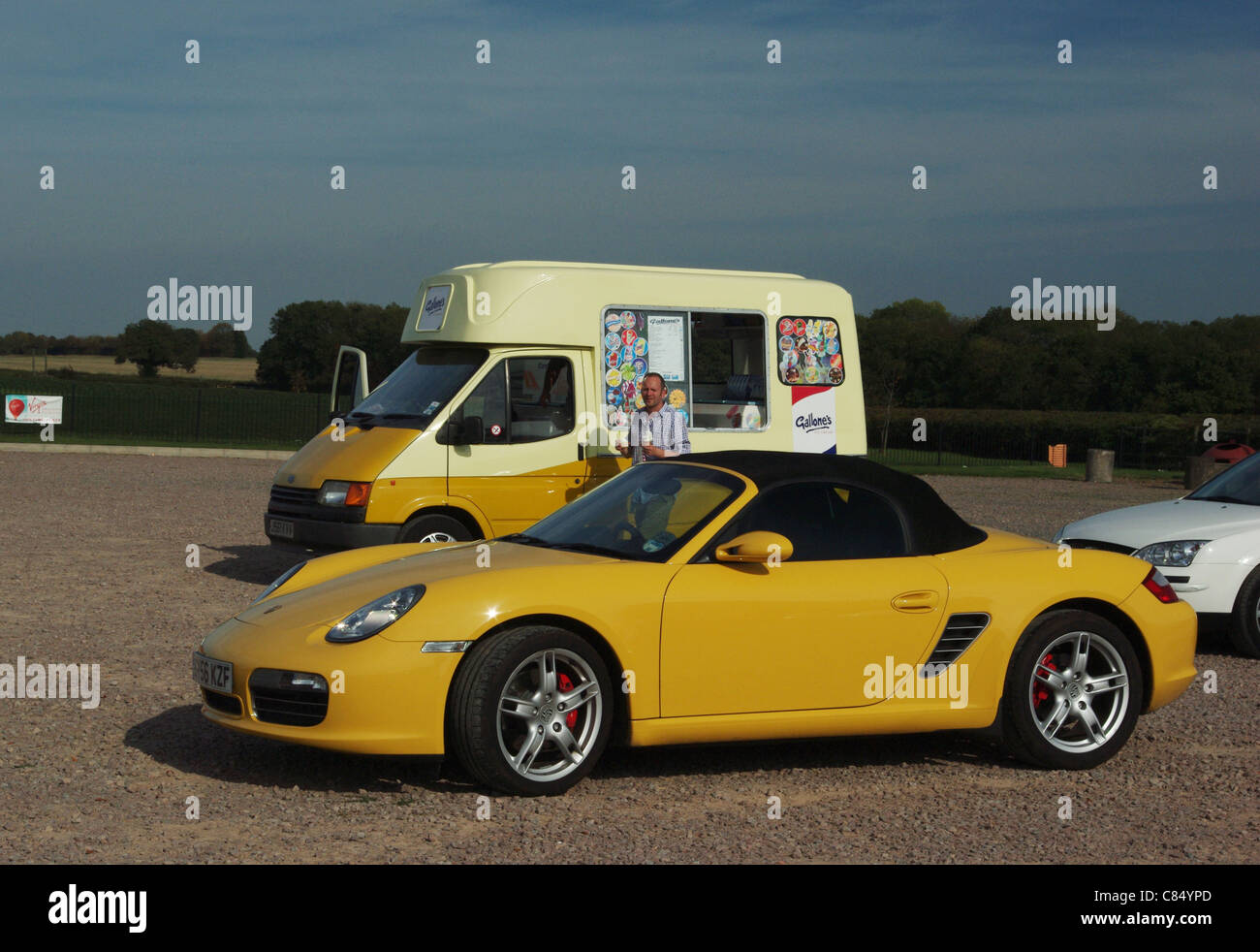 Porsche auto sportiva in primo piano, gelato van in background, sia in corrispondenza dei colori Foto Stock