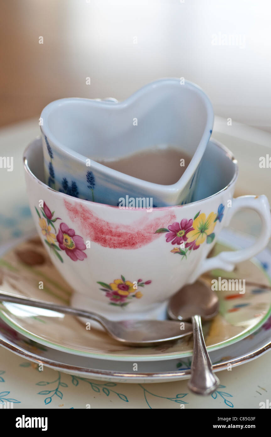 Confuso tazze di tè in ogni altro, uno di loro sbavature con il rossetto gli altri a forma di cuore Foto Stock