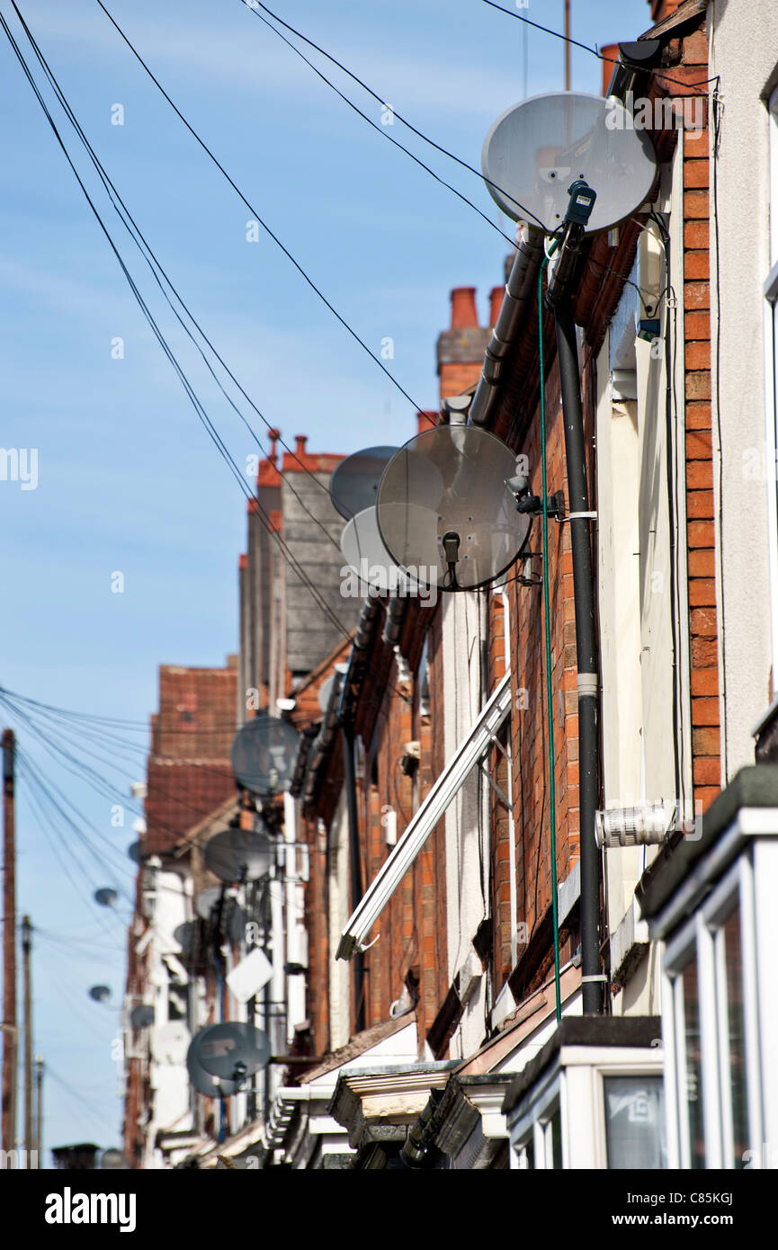 Antenne paraboliche disordine la parte anteriore del case su una strada britannica.Il formato verticale. Foto Stock