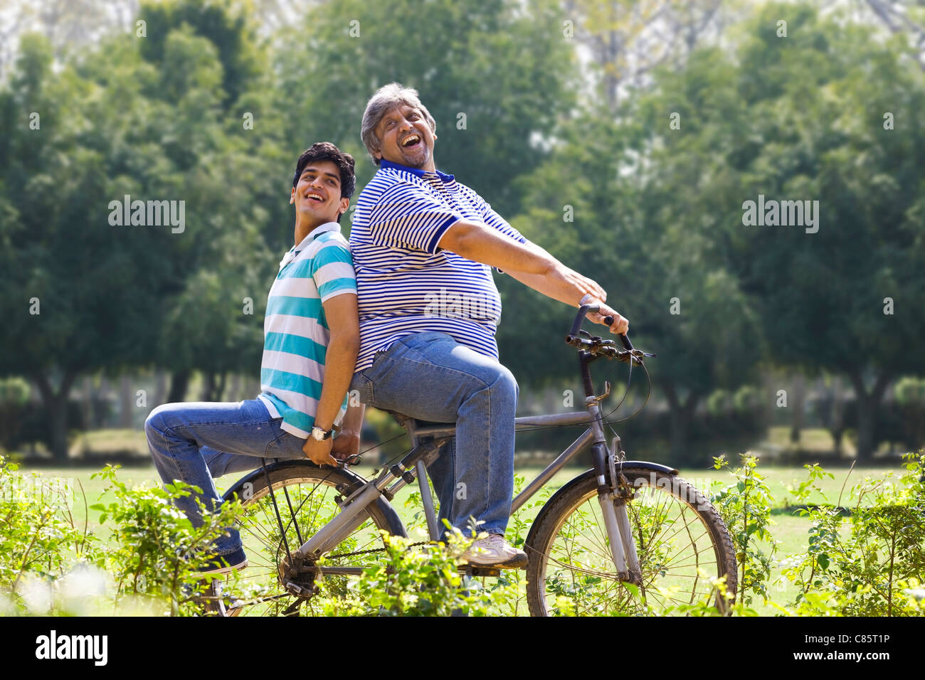 Padre di una bicicletta mentre figlio siede dietro Foto Stock