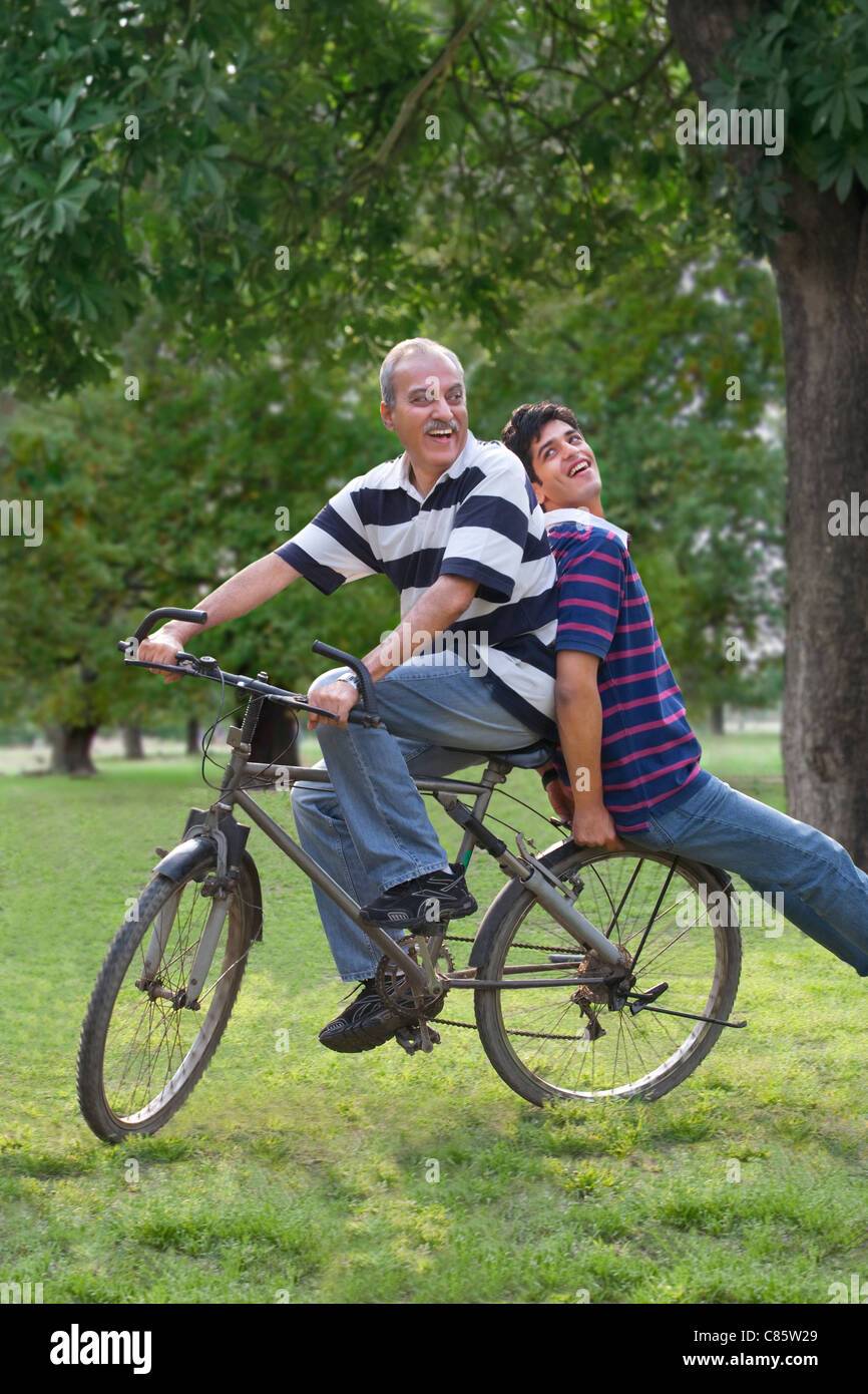 Padre di una bicicletta mentre figlio siede dietro Foto Stock