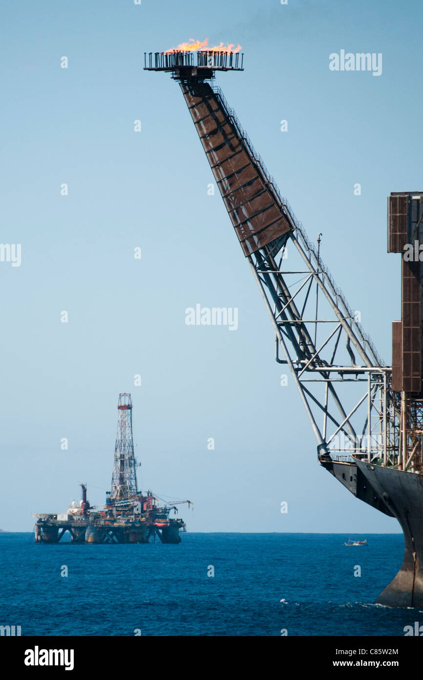 Vista di un impianto di trivellazione petrolifera campo con l'utilizzo di una FPSO sul primo piano. Campos Basin, offshore stato di Rio de Janeiro, costa del Brasile. Foto Stock