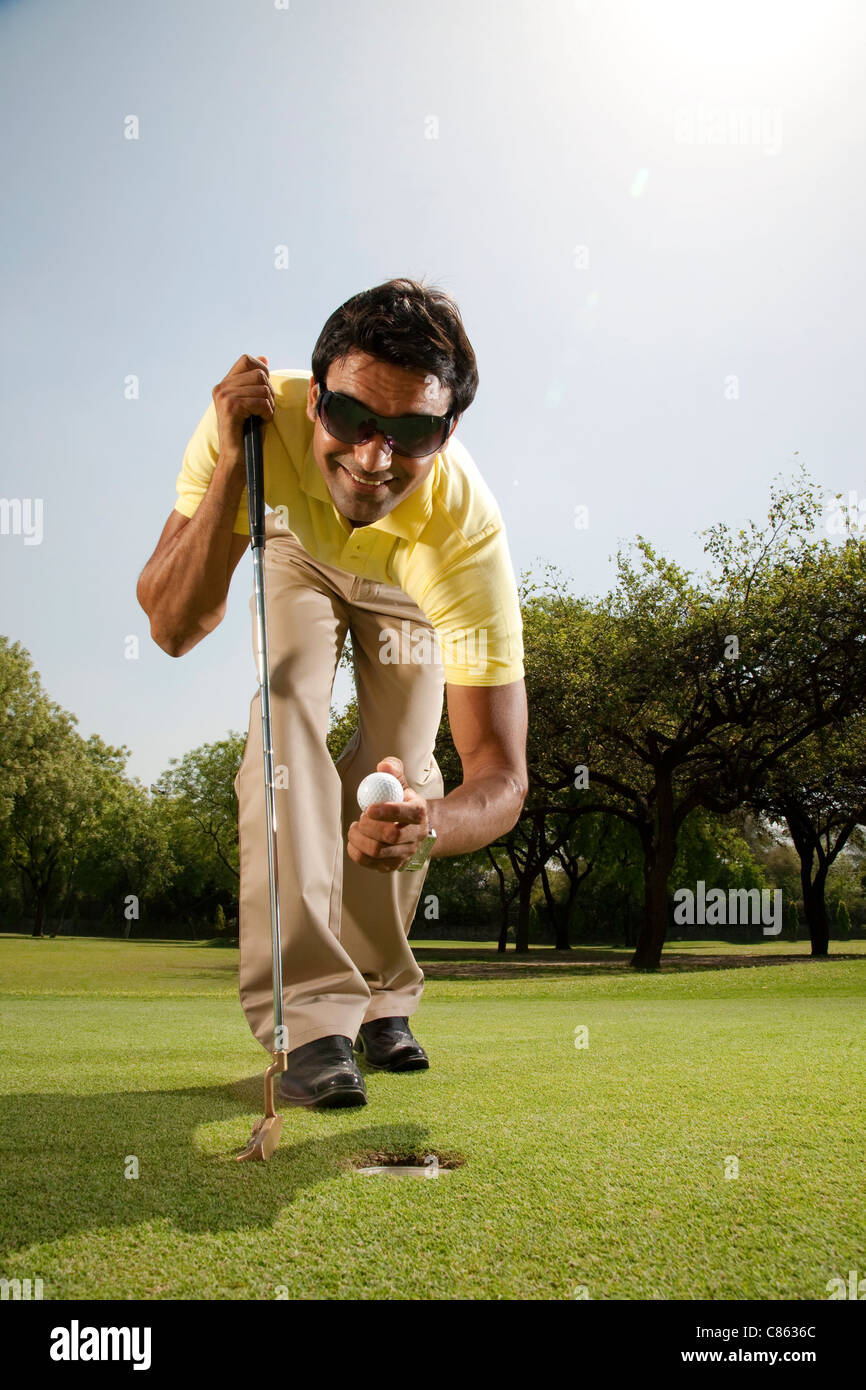 Uomo di prendere una pallina da golf al di fuori di un foro Foto Stock