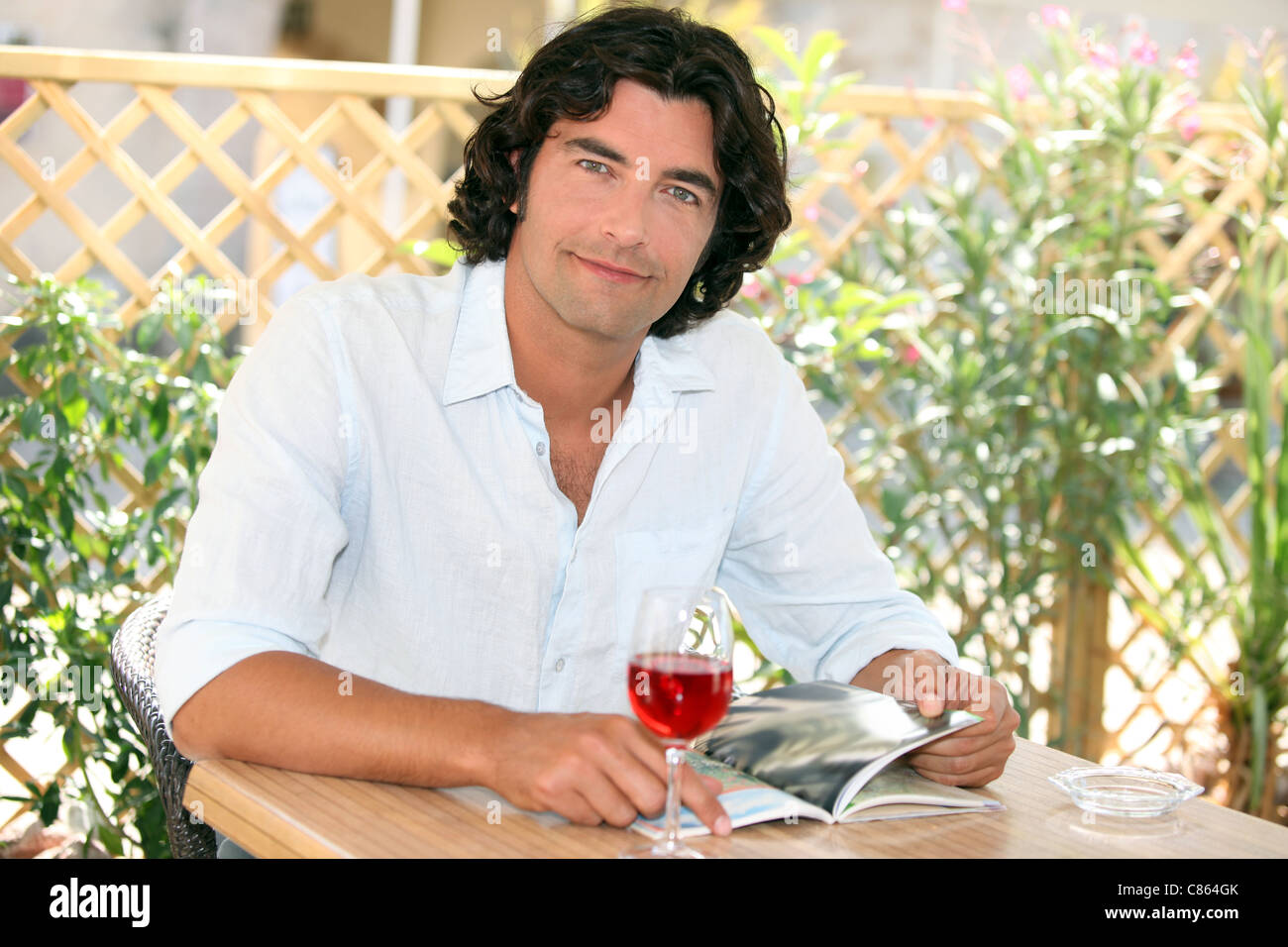 L'uomo gustando un bicchiere di vino in un cafe' all'aperto Foto Stock