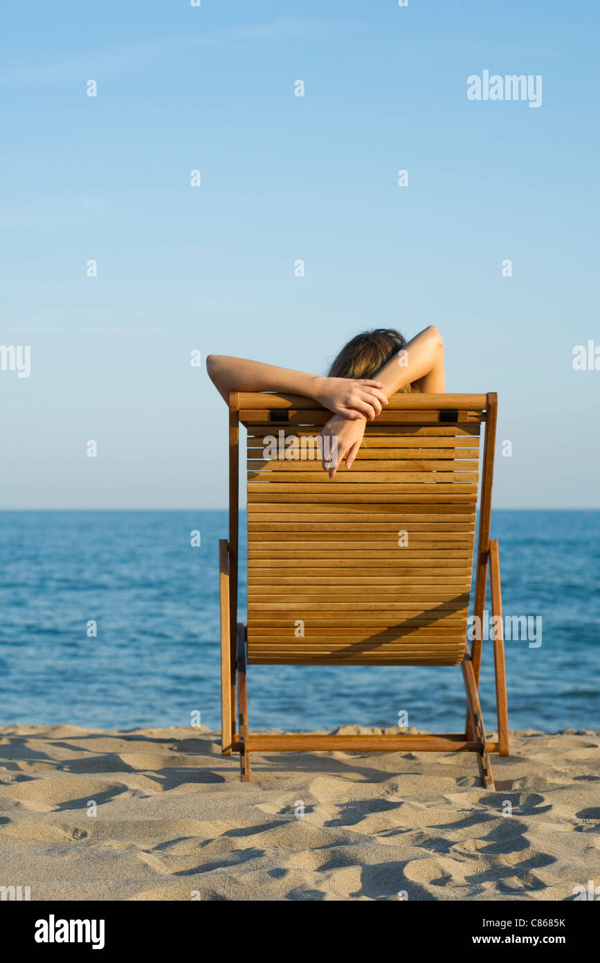 Donna rilassante in sedia a sdraio in spiaggia Foto Stock