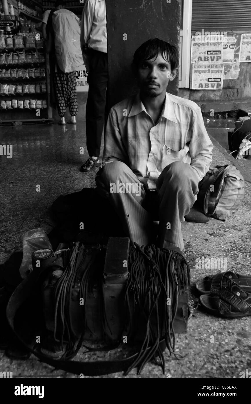 Una calzatura uomo di riparazione in corrispondenza di una stazione di autobus in Dharamsala, India Foto Stock