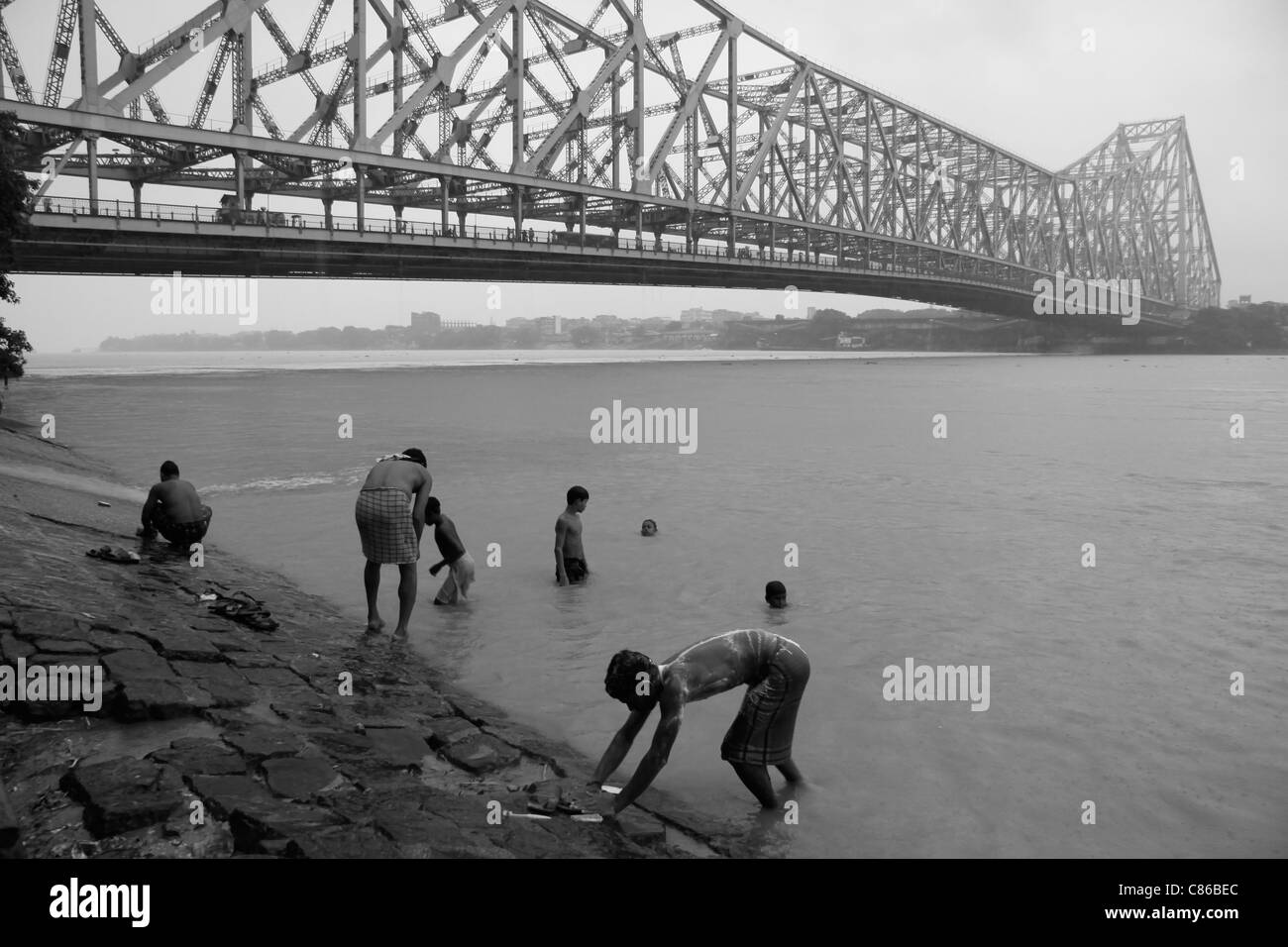 Gli uomini indù bagnarsi nel Fiume Hooghly sotto quella di Howrah Bridge in Kolkata (Calcutta), India Foto Stock