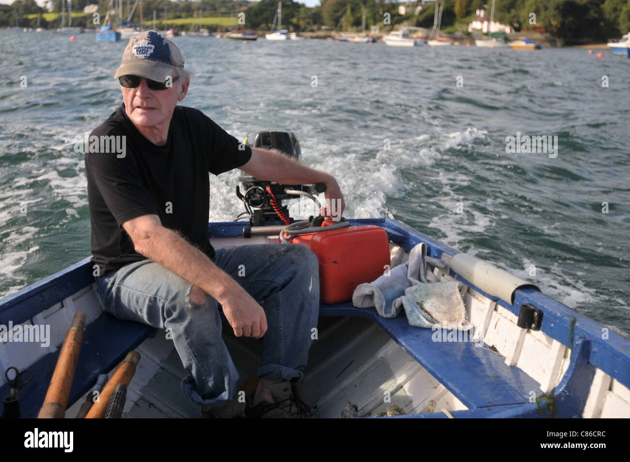 Un uomo nella sua metà degli anni sessanta sulla sua barca solo lasciando Falmouth Foto Stock