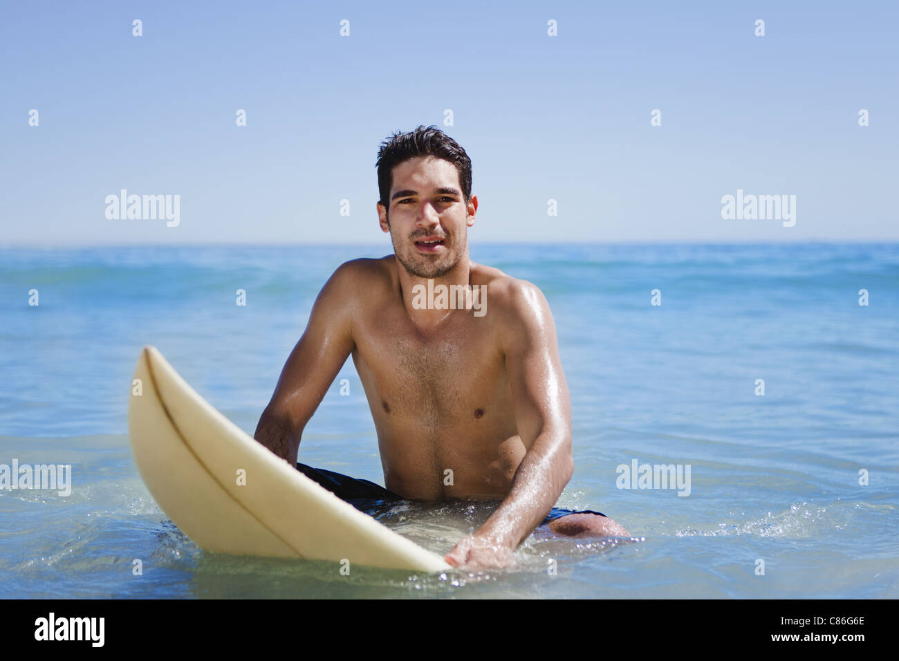 Uomo seduto sulla tavola da surf in acqua Foto Stock