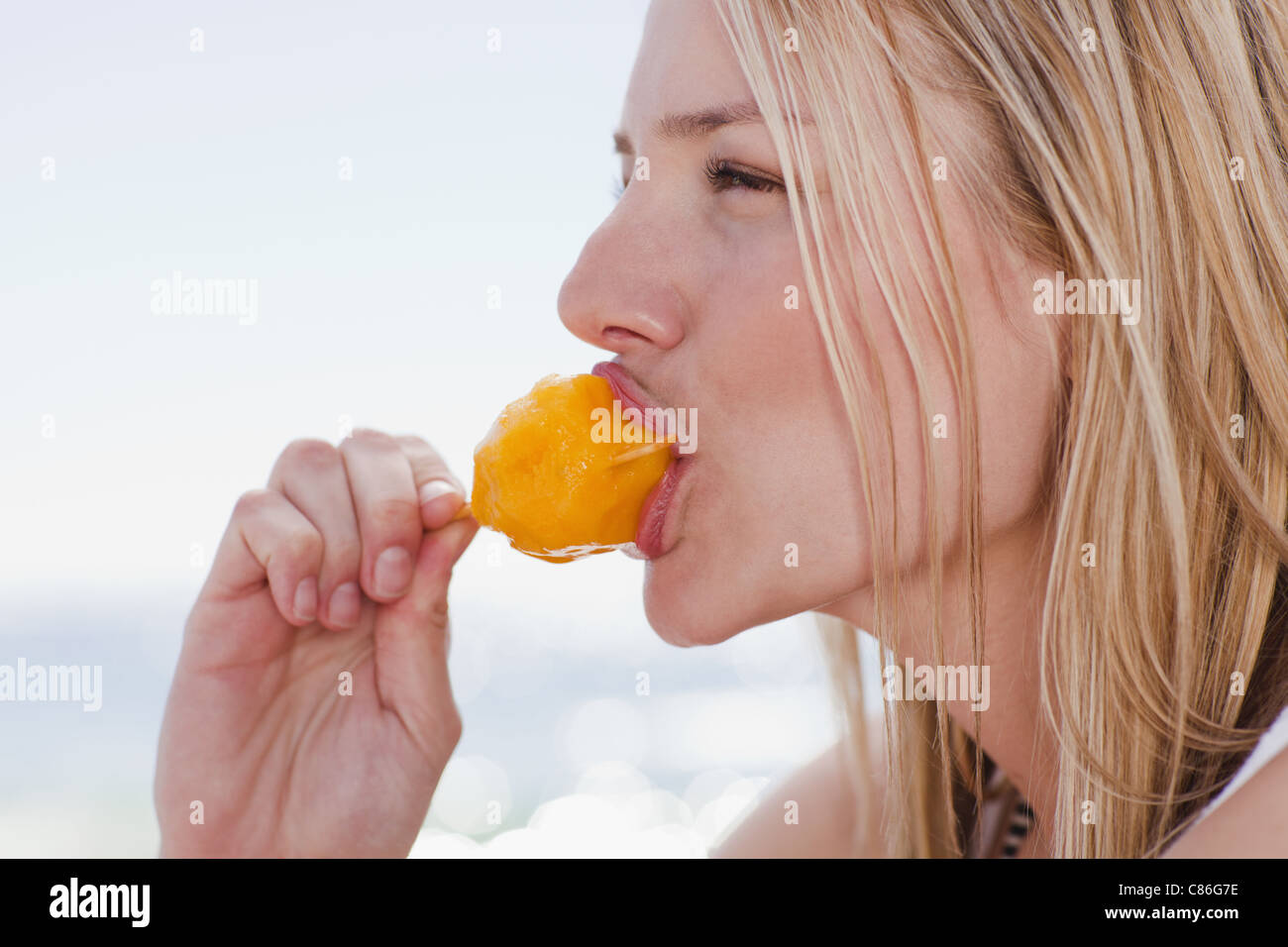 Donna di mangiare ghiaccioli sulla spiaggia Foto Stock